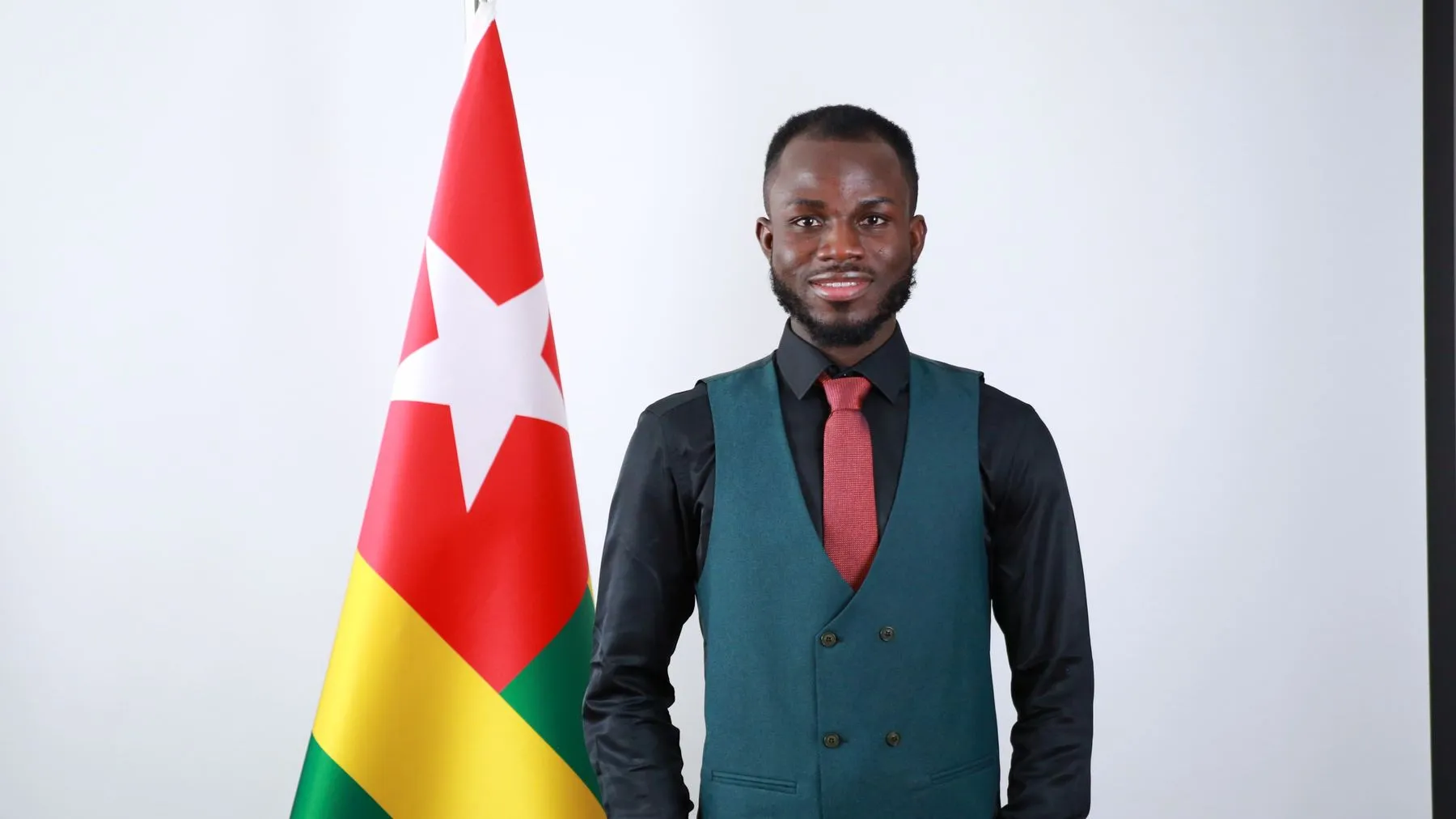 Faroukou Mintoiba beside the flag of Togo